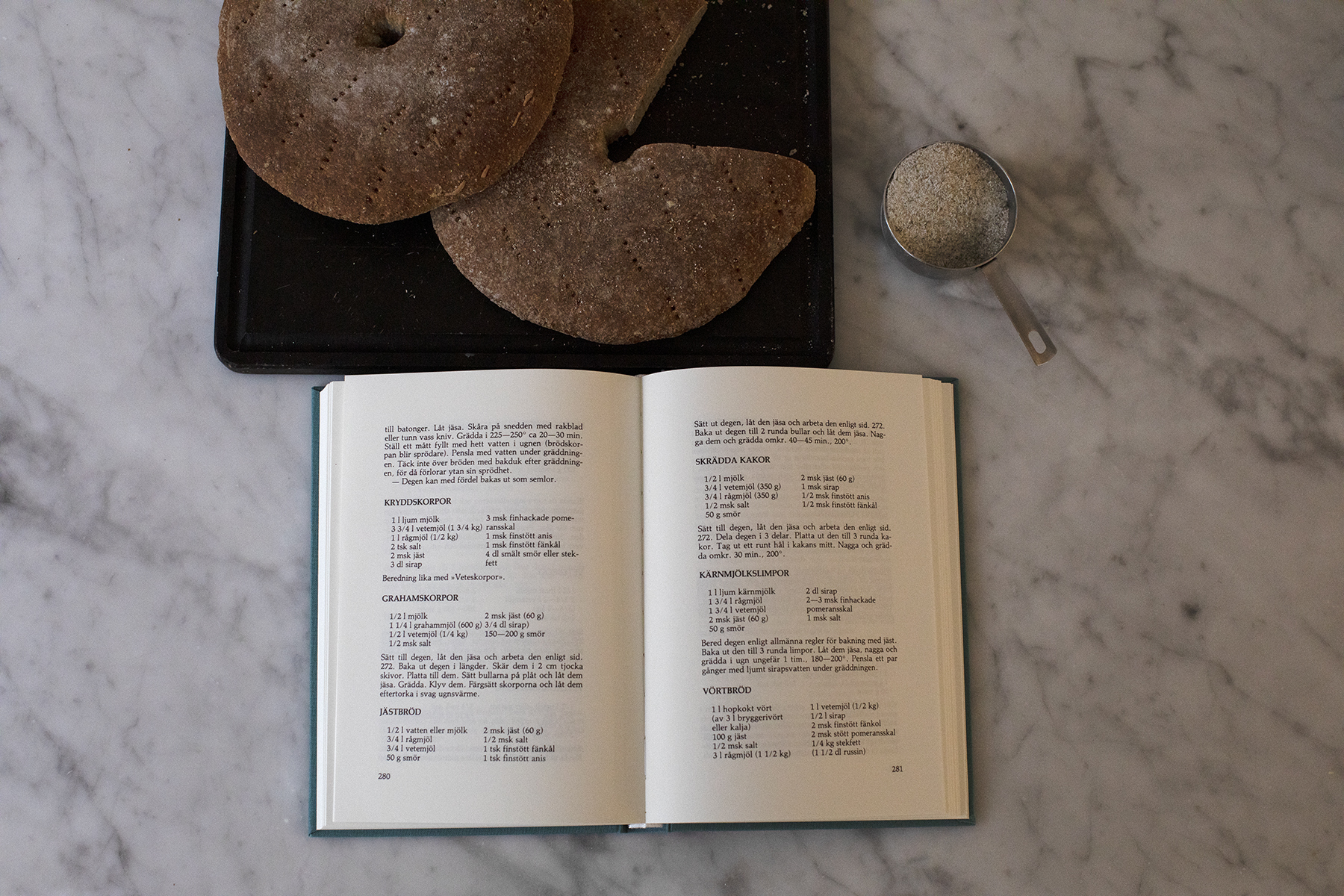 Marthas kokbok, två bröd på en skärbräda och ett decilitermått med mjöl